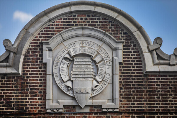 Carved stone Penn insignia embedded into a brick arch entrance way to Franklin field